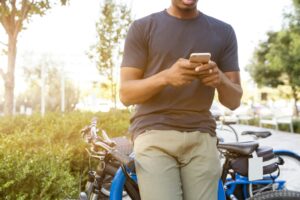 tcpa lawsuits tcpa texts man holding phone next to bikes telemarketing CCPA