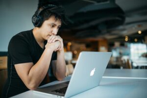 FTC subscriptions man looking distressed looking at laptop with headphones on