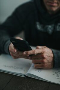 mature man holding phone over a notebook TCR registraton