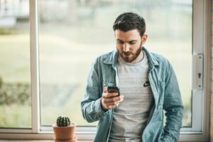 man holding phone next to window telemarketing hours