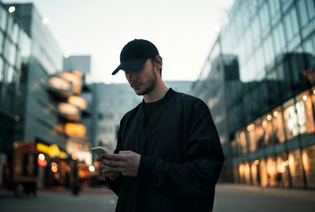 man in black baseball cap on his phone in middle of street looks like a city street CIPA wiretap telemarketing data privacy