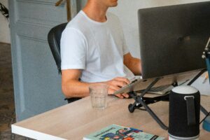 man at his desk on the computer in a white tshirt