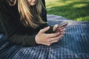 blonde woman sitting outside on her phone looks liek text messaging telemarketing tcpa law