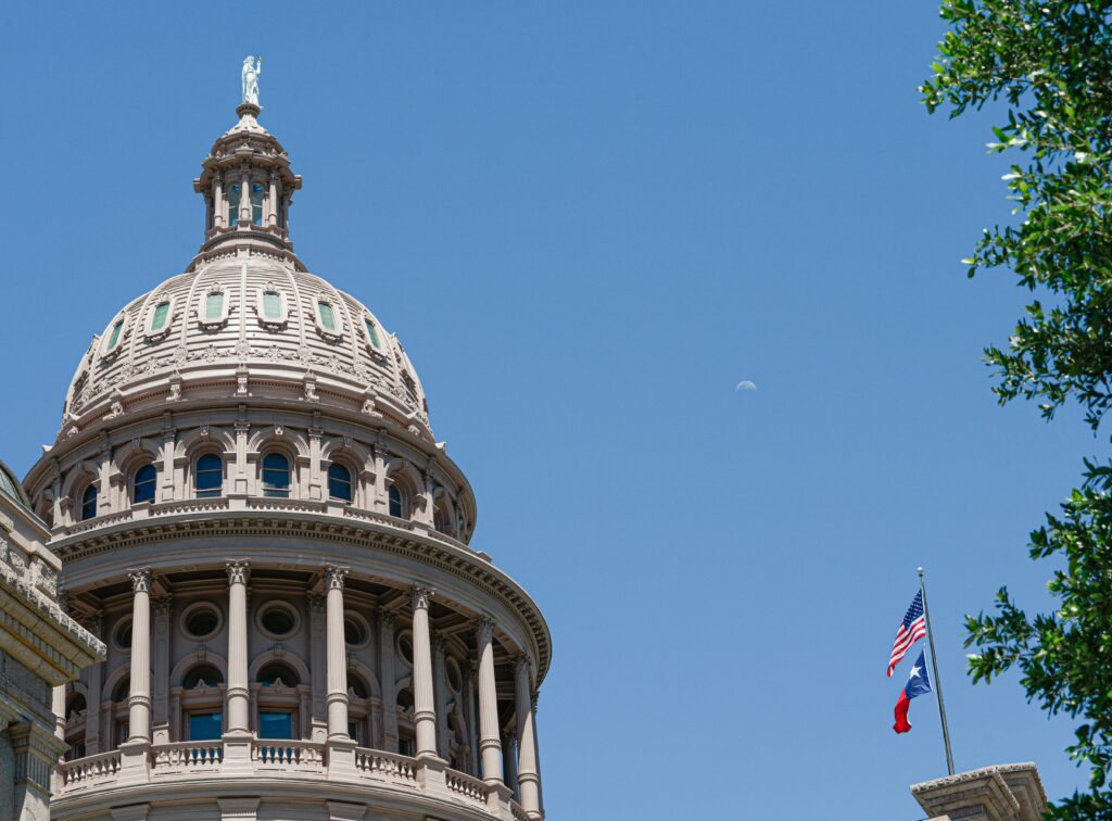 tcpa texas texas capitol building with american flag and texas flag on flag pole in front