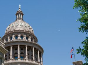 tcpa texas texas capitol building with american flag and texas flag on flag pole in front