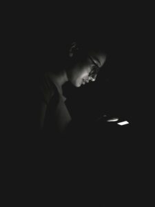 girl with glasses on looking at her phone at night