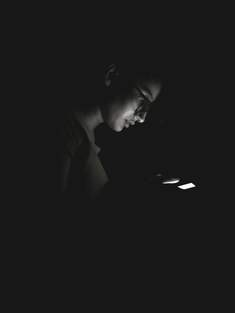 girl with glasses on looking at her phone at night